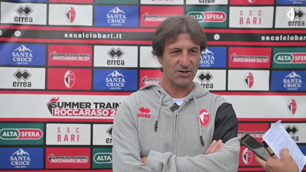 Allenatore a braccia conserte mentre risponde