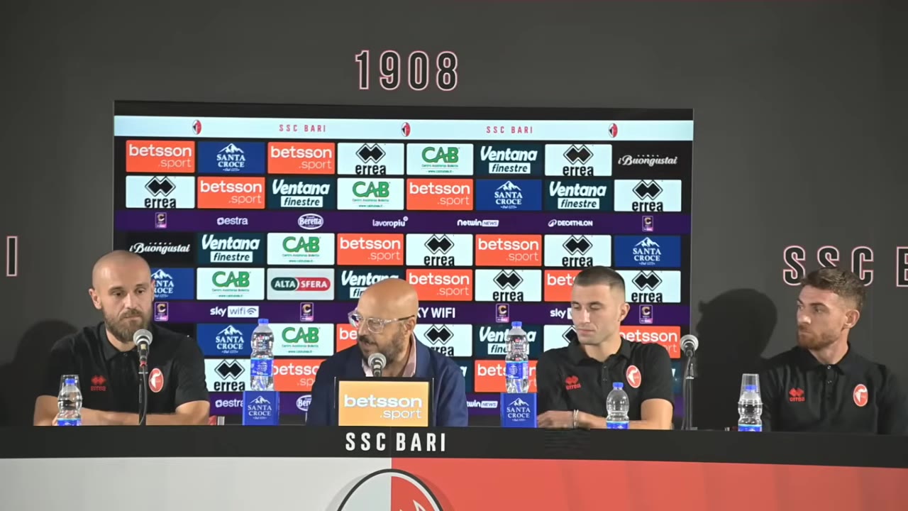 Quattro persone al tavolo di conferenza stampa